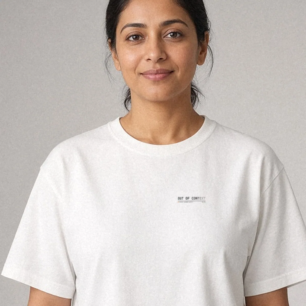 AI-generated render of the Out of Context Tee in White on a model, front view: small left-chest print reading OUT OF CONTEXT, the last letters fading out.